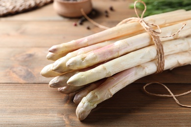 Photo of Bunch of fresh white asparagus on wooden table, closeup