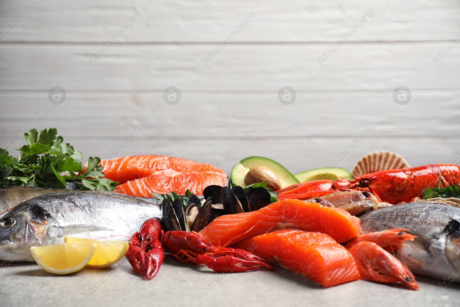 Photo of Fresh raw fish and different seafood on light grey table