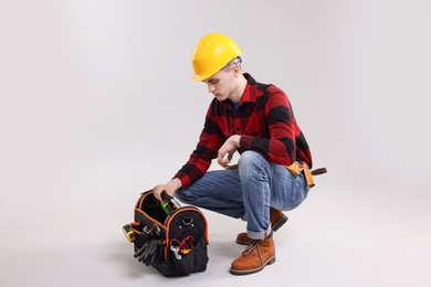 Professional repairman with tool box on light grey background