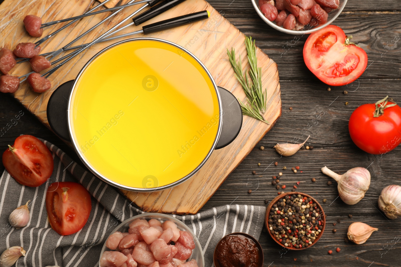 Photo of Flat lay composition with oil pot and meat fondue ingredients on wooden background