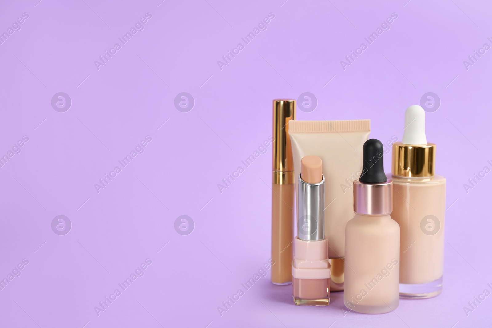 Photo of Foundation makeup products on violet background, space for text. Decorative cosmetics