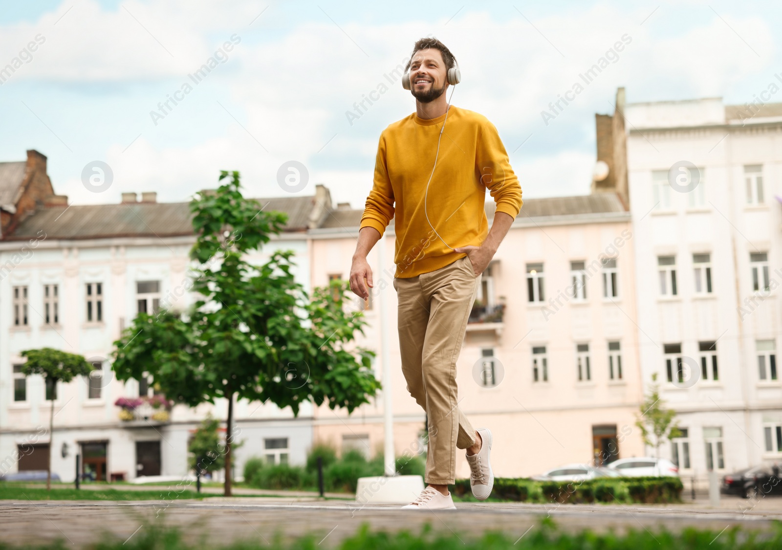 Photo of Handsome man with headphones walking on city street