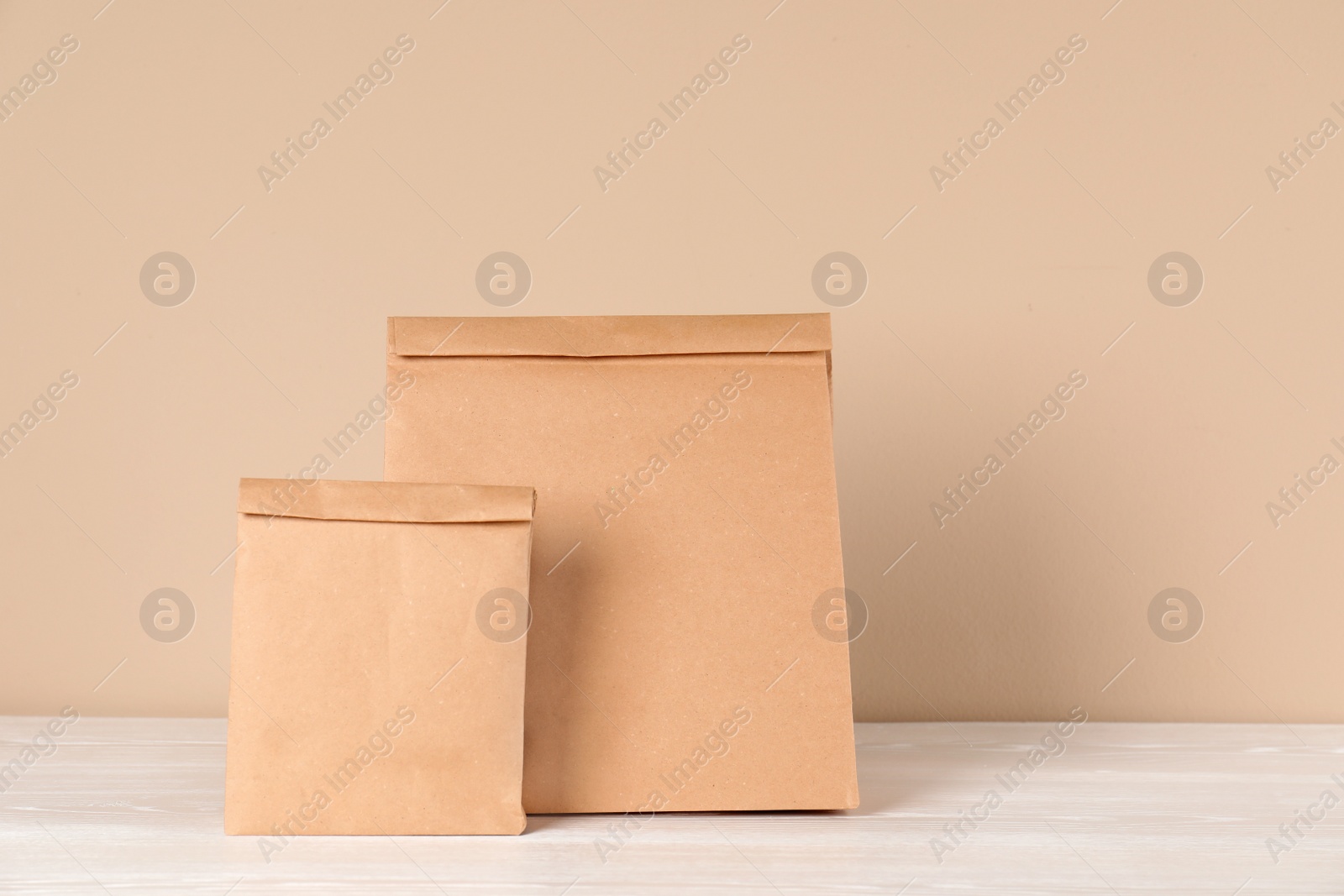 Photo of Paper bags on table against color background. Mockup for design