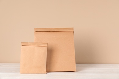 Photo of Paper bags on table against color background. Mockup for design