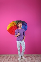 Man with rainbow umbrella near color wall