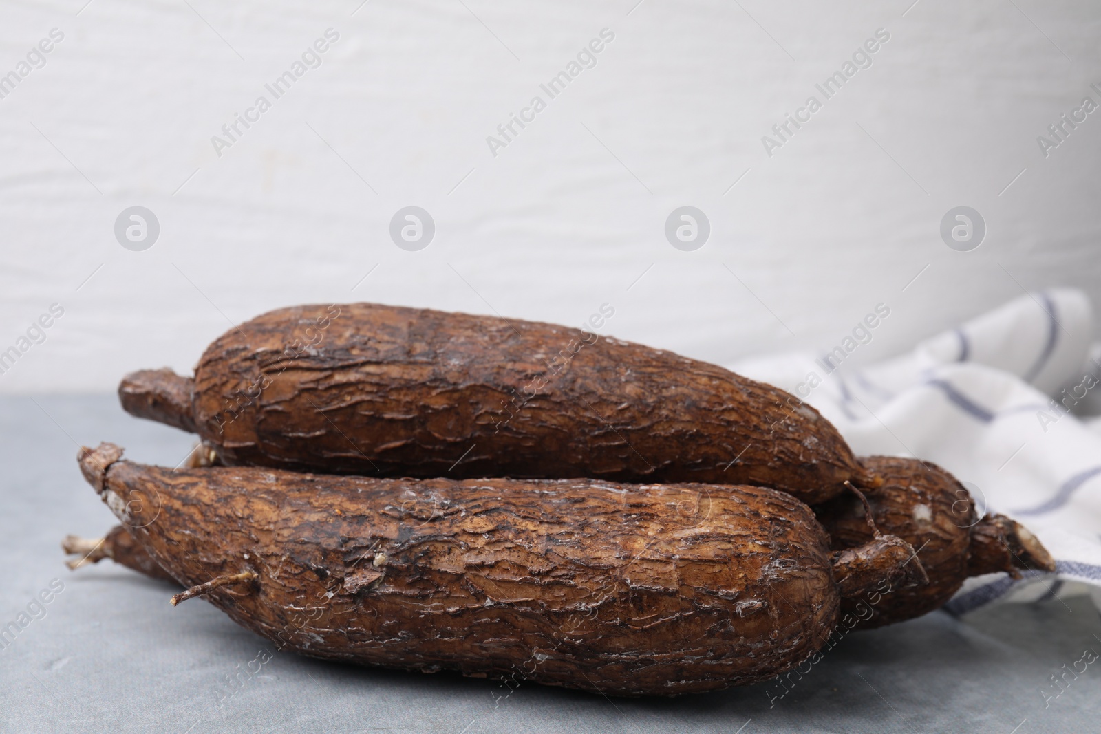 Photo of Fresh whole cassava roots on grey table, closeup