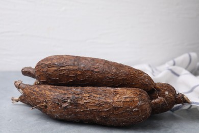 Photo of Fresh whole cassava roots on grey table, closeup
