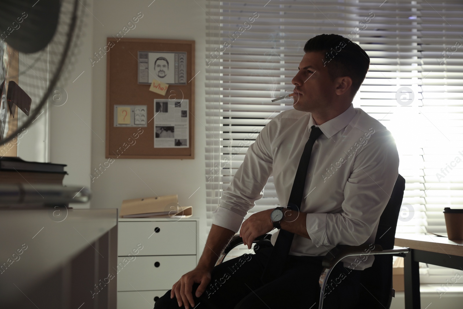 Photo of Professional detective smoking cigarette in his office