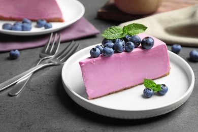 Photo of Plate with piece of tasty blueberry cake on grey table