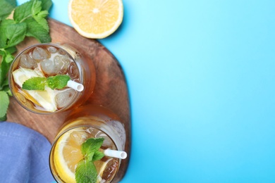 Photo of Delicious iced tea with lemon and mint on light blue background, flat lay. Space for text