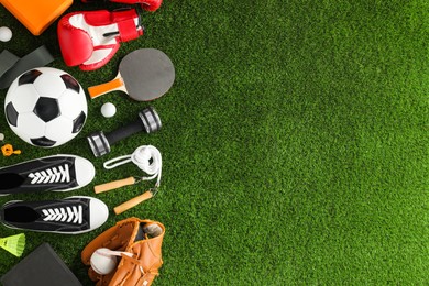 Photo of Different sport equipment and sneakers on green grass, flat lay. Space for text