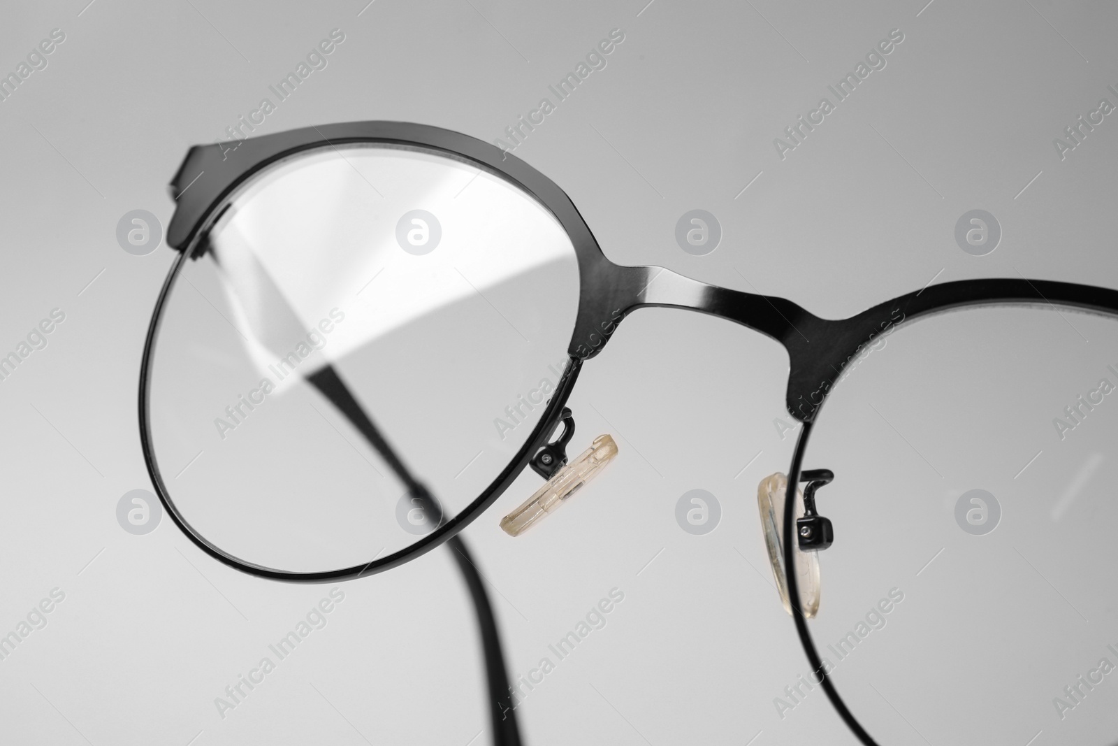 Photo of Stylish pair of glasses with black frame on beige background, closeup