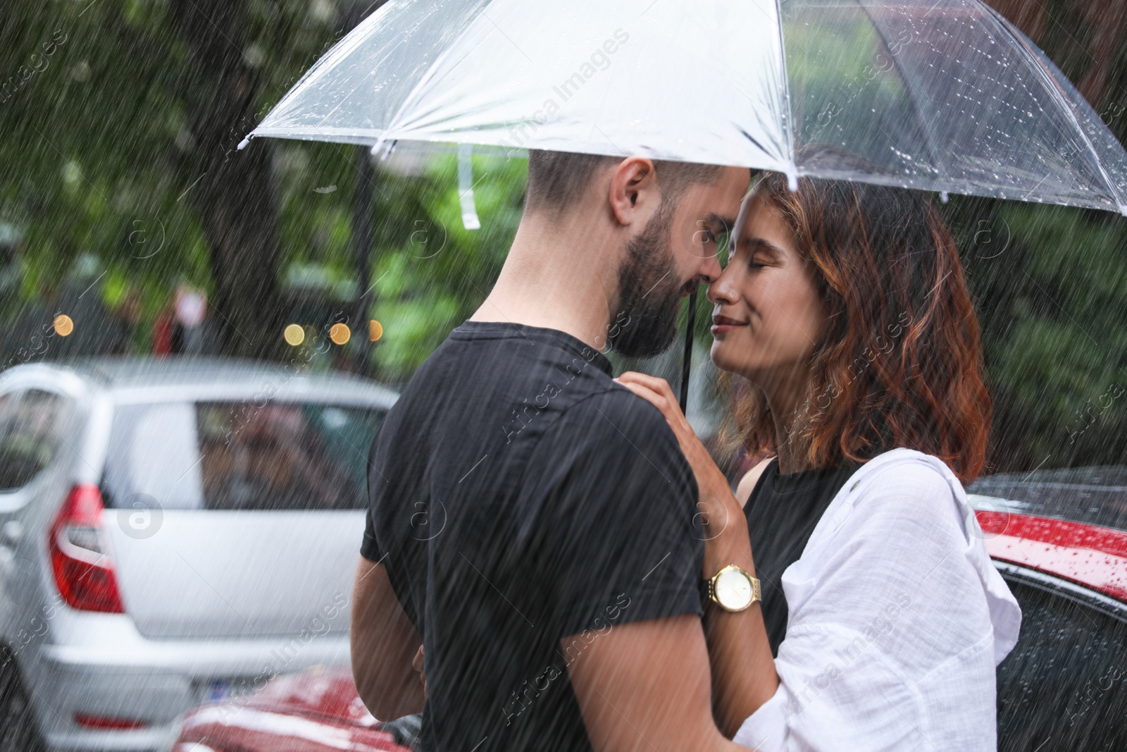 Photo of Young couple with umbrella enjoying time together under rain on city street