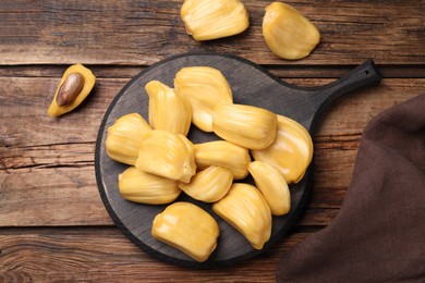 Delicious exotic jackfruit bulbs on wooden table, flat lay