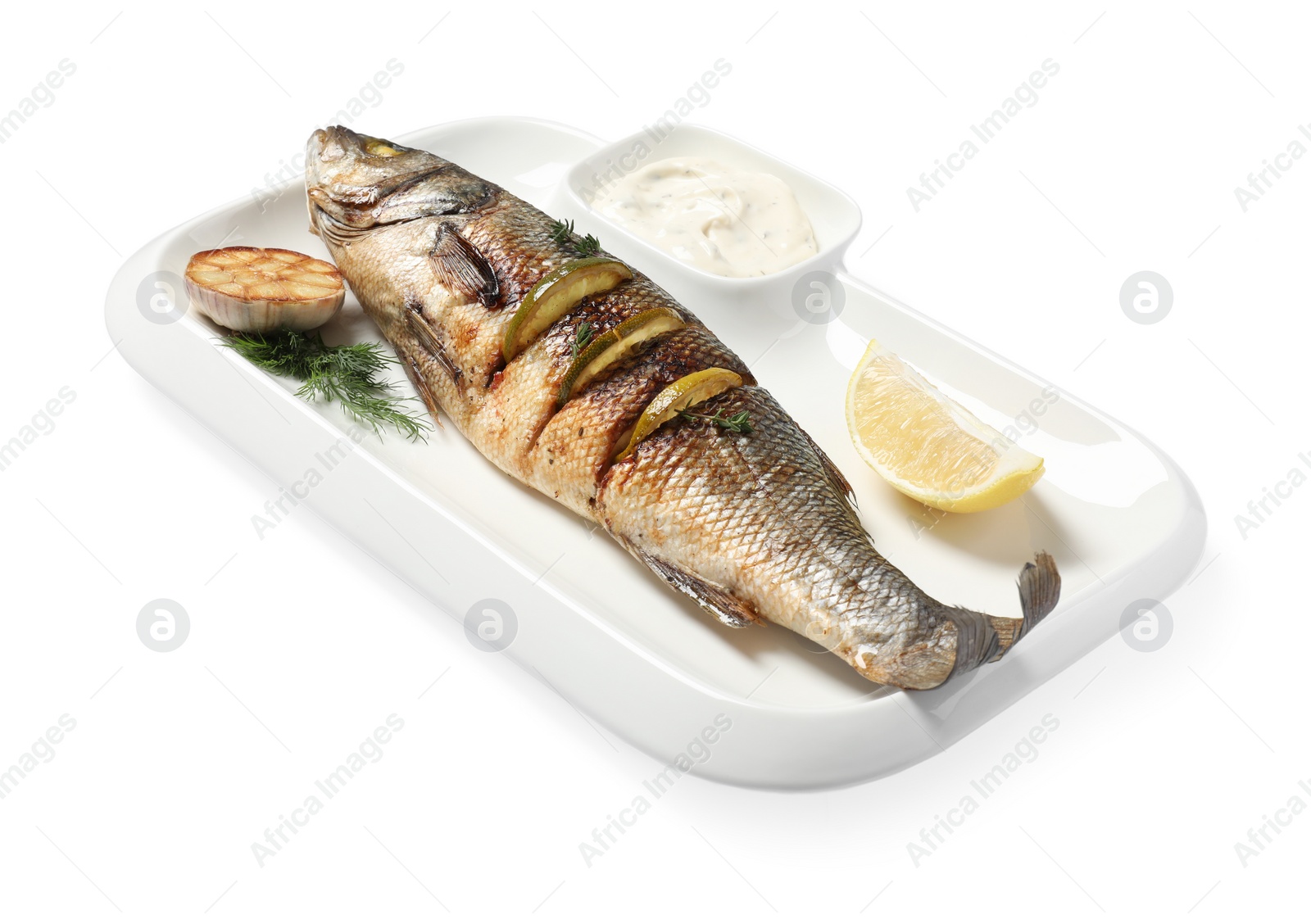 Photo of Plate with delicious baked sea bass fish, garlic, slice of lemon and sauce on white background