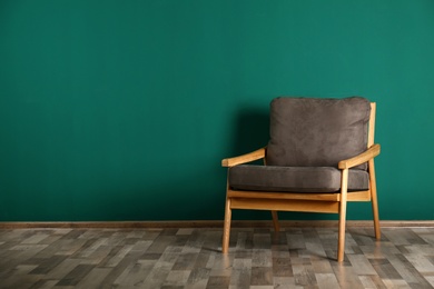 Stylish armchair near color wall, space for text. Interior design