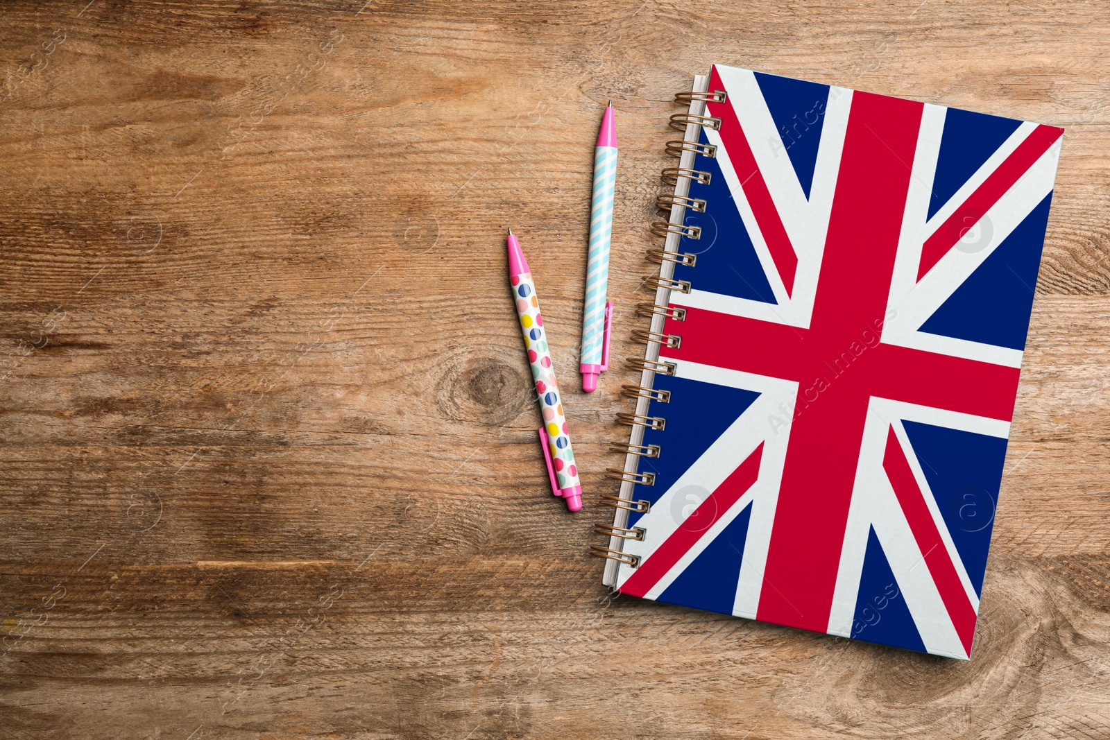 Image of Stylish notebook and pens on wooden table, flat lay with space for text. Learning English