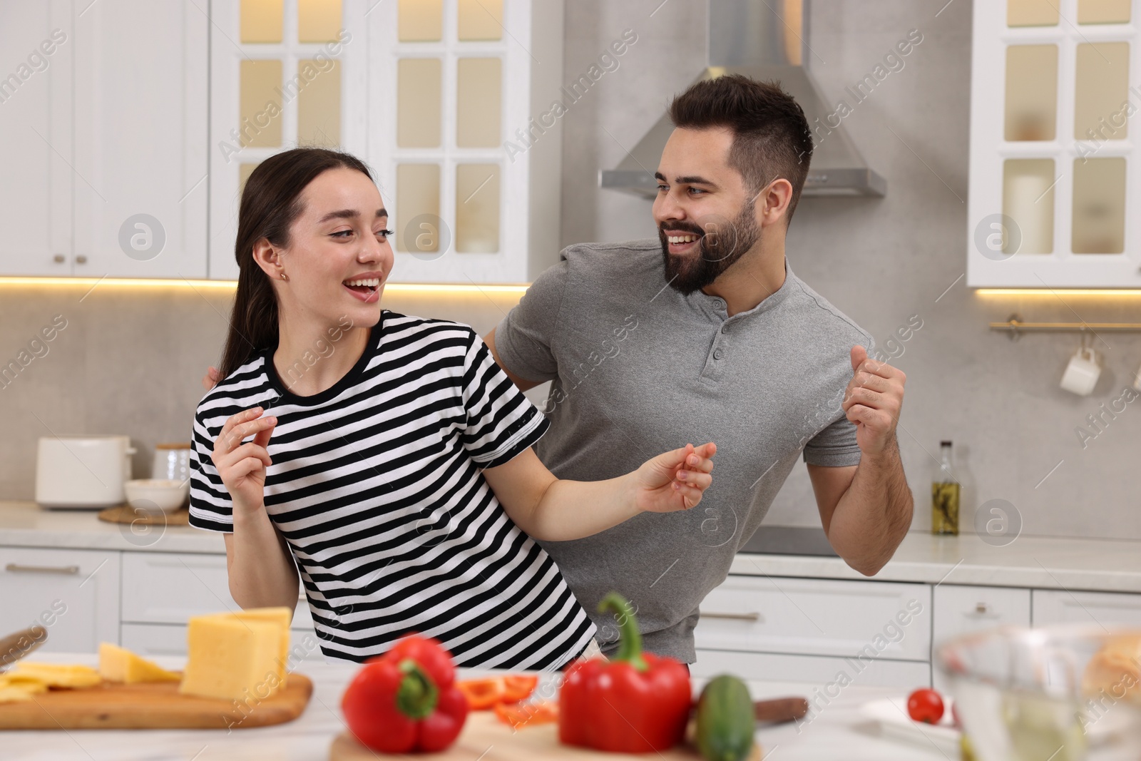 Photo of Happy lovely couple dancing together while cooking in kitchen