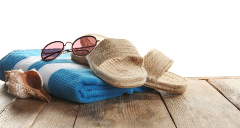 Photo of Towel, shoes, sea shell and sunglasses on wooden table. Beach accessories