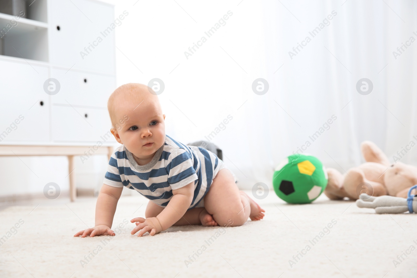 Photo of Cute little baby crawling on carpet indoors