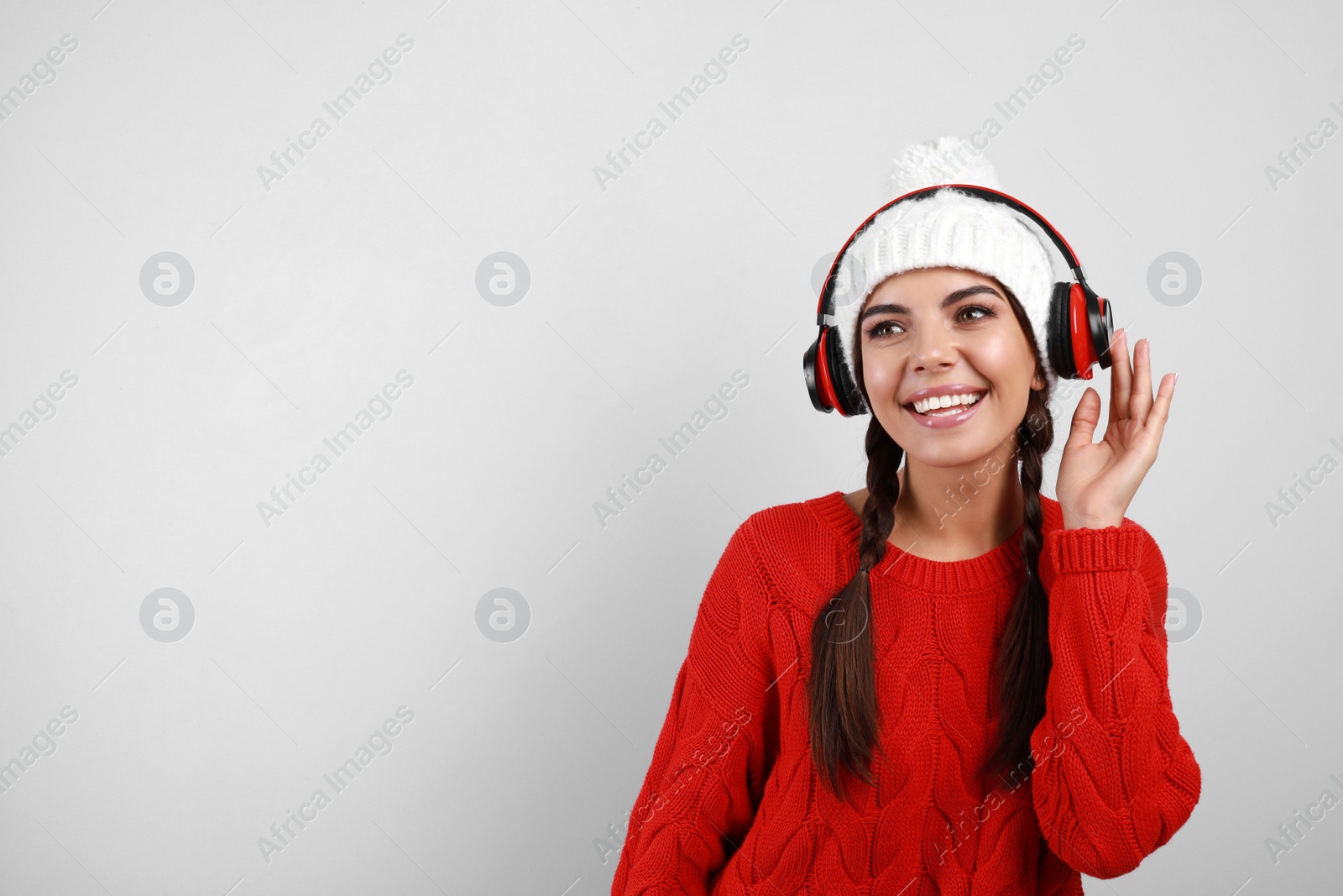 Photo of Young woman listening to music with headphones on grey background, space for text