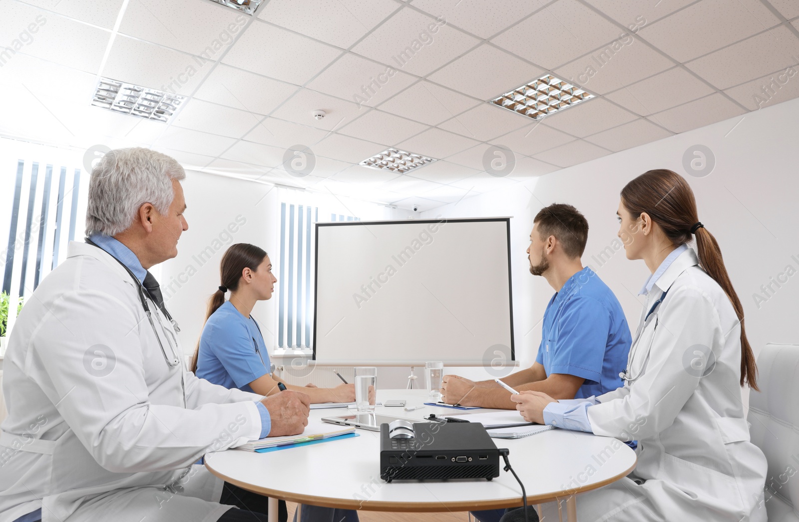 Photo of Team of doctors using video projector during conference indoors