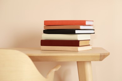 Photo of Stack of different hardcover books on wooden table indoors