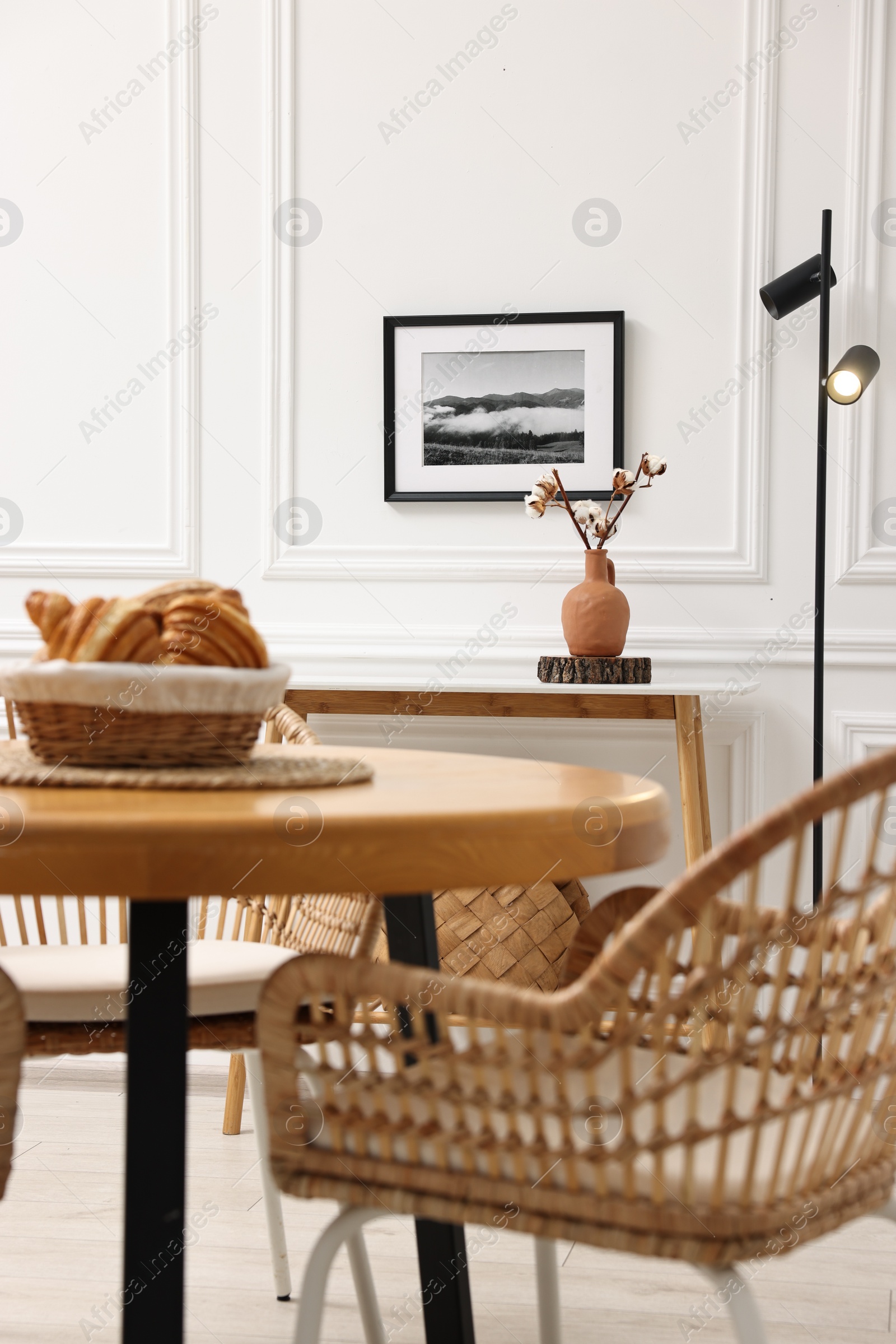 Photo of Tasty croissants on table and wicker chairs in dining room. Interior design