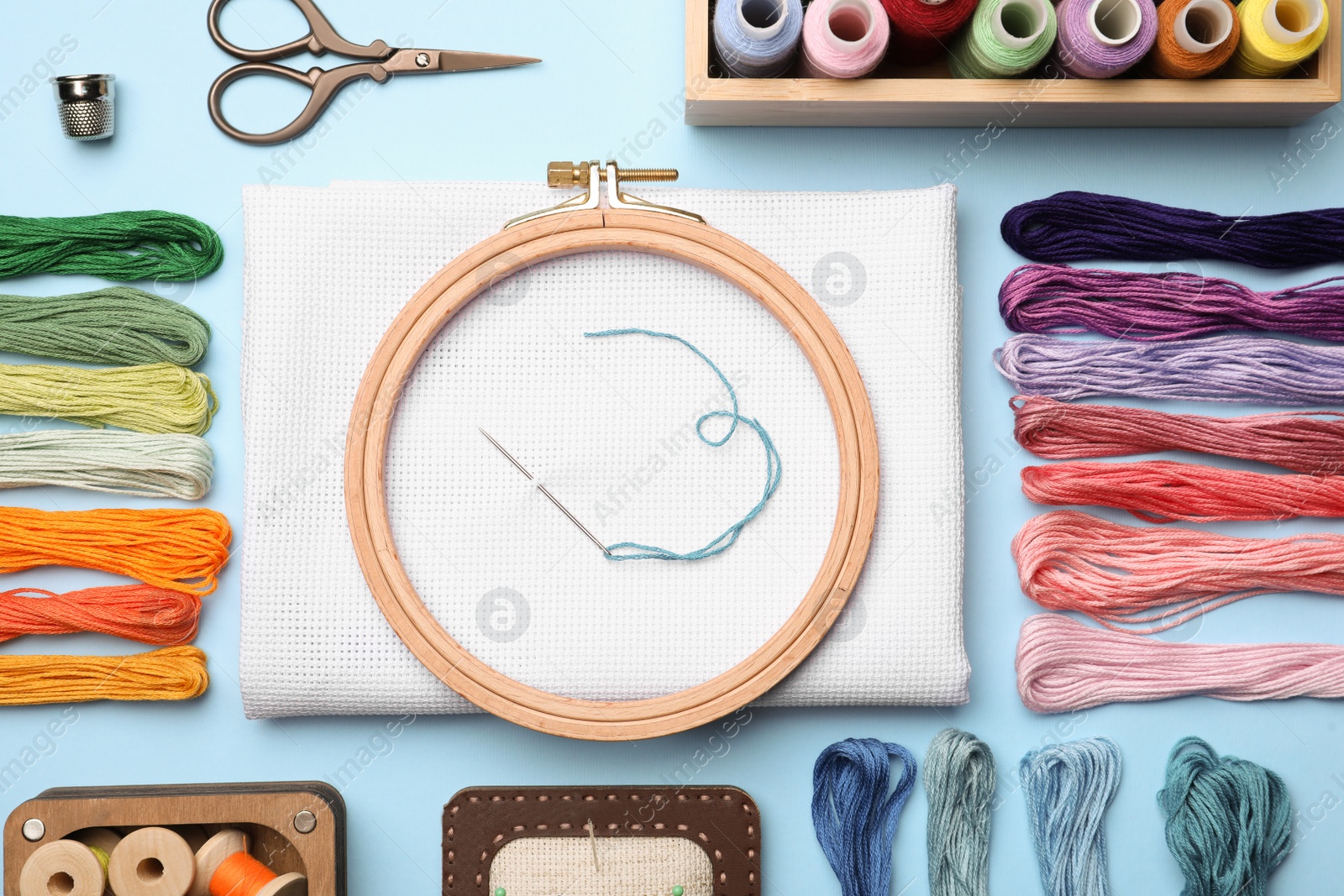 Photo of Flat lay composition with embroidery accessories on light blue background