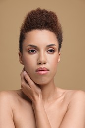 Portrait of beautiful young woman with glamorous makeup on light brown background