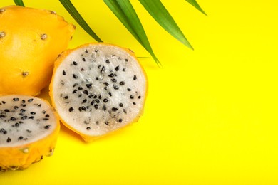 Photo of Delicious cut and whole dragon fruits (pitahaya) on yellow background, closeup. Space for text