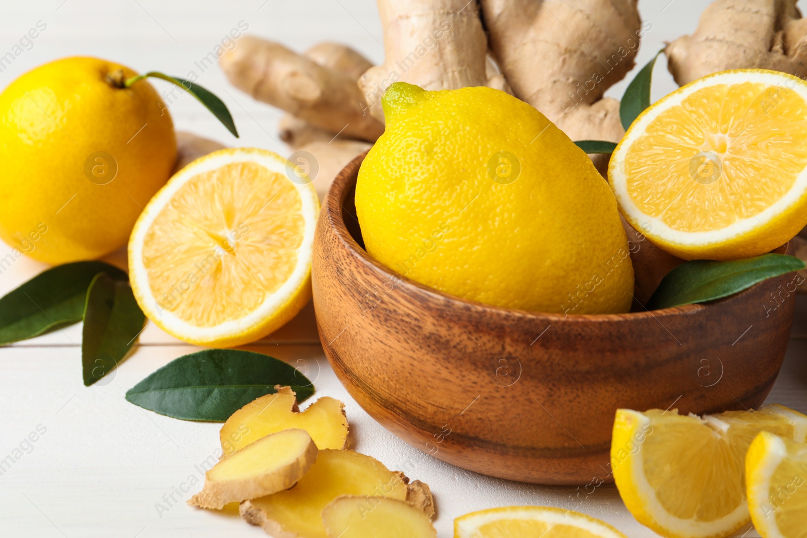 Photo of Fresh lemons and ginger on white wooden table, closeup