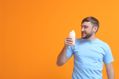 Young man with glass of delicious milk shake on color background