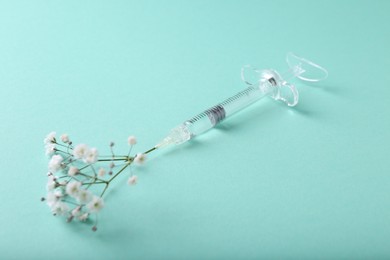 Cosmetology. Medical syringe and gypsophila on turquoise background