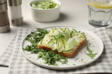Photo of Tasty cucumber sandwich with seasoning and arugula on table