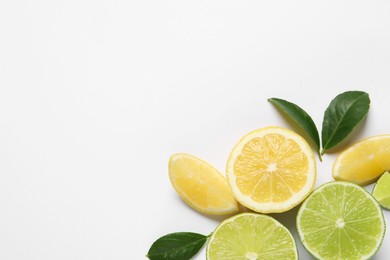 Photo of Fresh ripe lemons, limes and green leaves on white background, top view