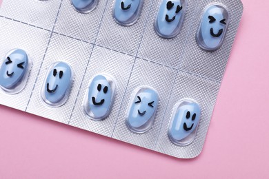 Photo of Blister of antidepressant pills with funny faces on pink background, closeup