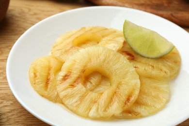 Tasty grilled pineapple slices and piece of lime on table, closeup