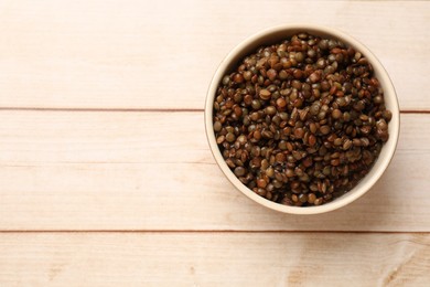 Delicious lentils in bowl on wooden table, top view. Space for text