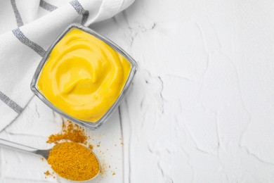 Tasty curry sauce and powder on white textured table, flat lay. Space for text