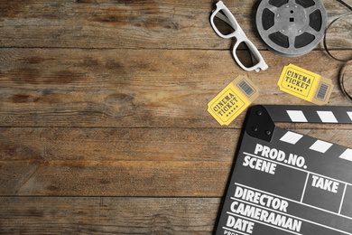 Photo of Flat lay composition with clapperboard, cinema tickets and 3d glasses on wooden table, space for text