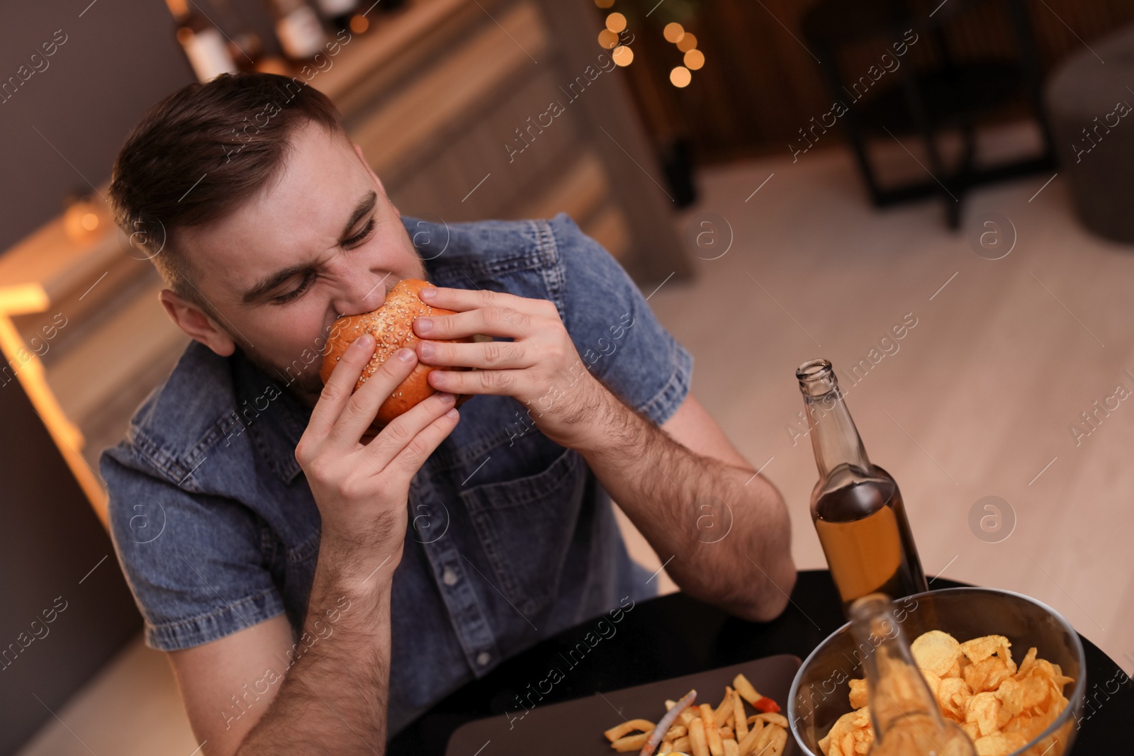 Photo of Young man eating tasty burger in cafe