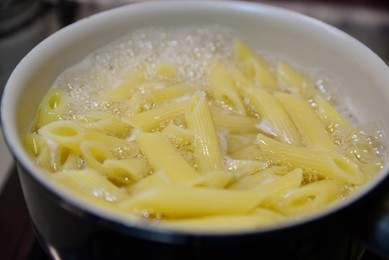 Cooking tasty pasta in pot, closeup view