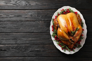 Platter of cooked turkey with garnish on wooden background, top view. Space for text