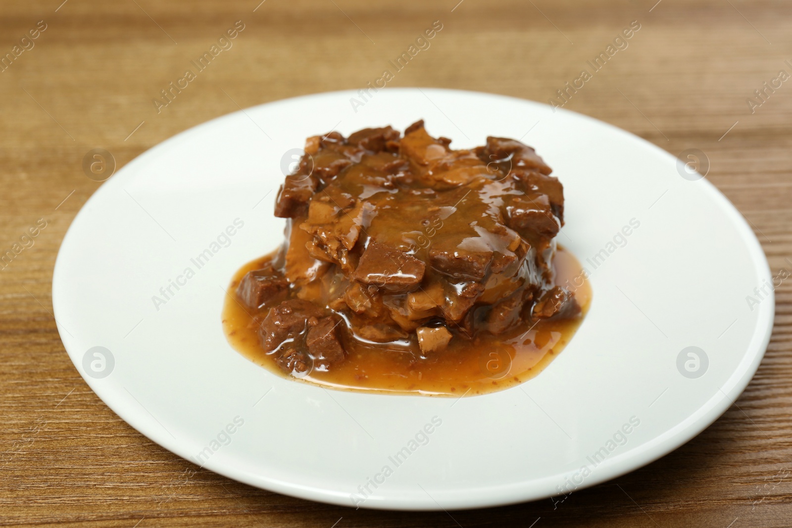 Photo of Plate with wet pet food on wooden table