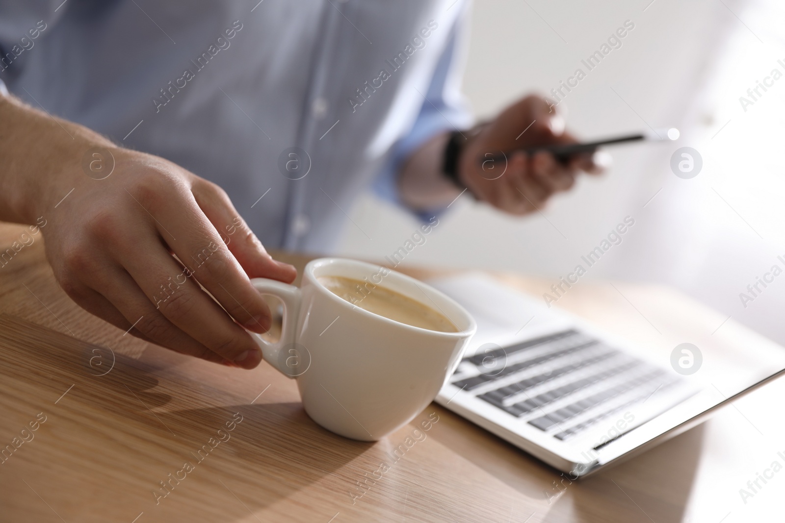 Photo of Man with cup of coffee at table indoors, closeup