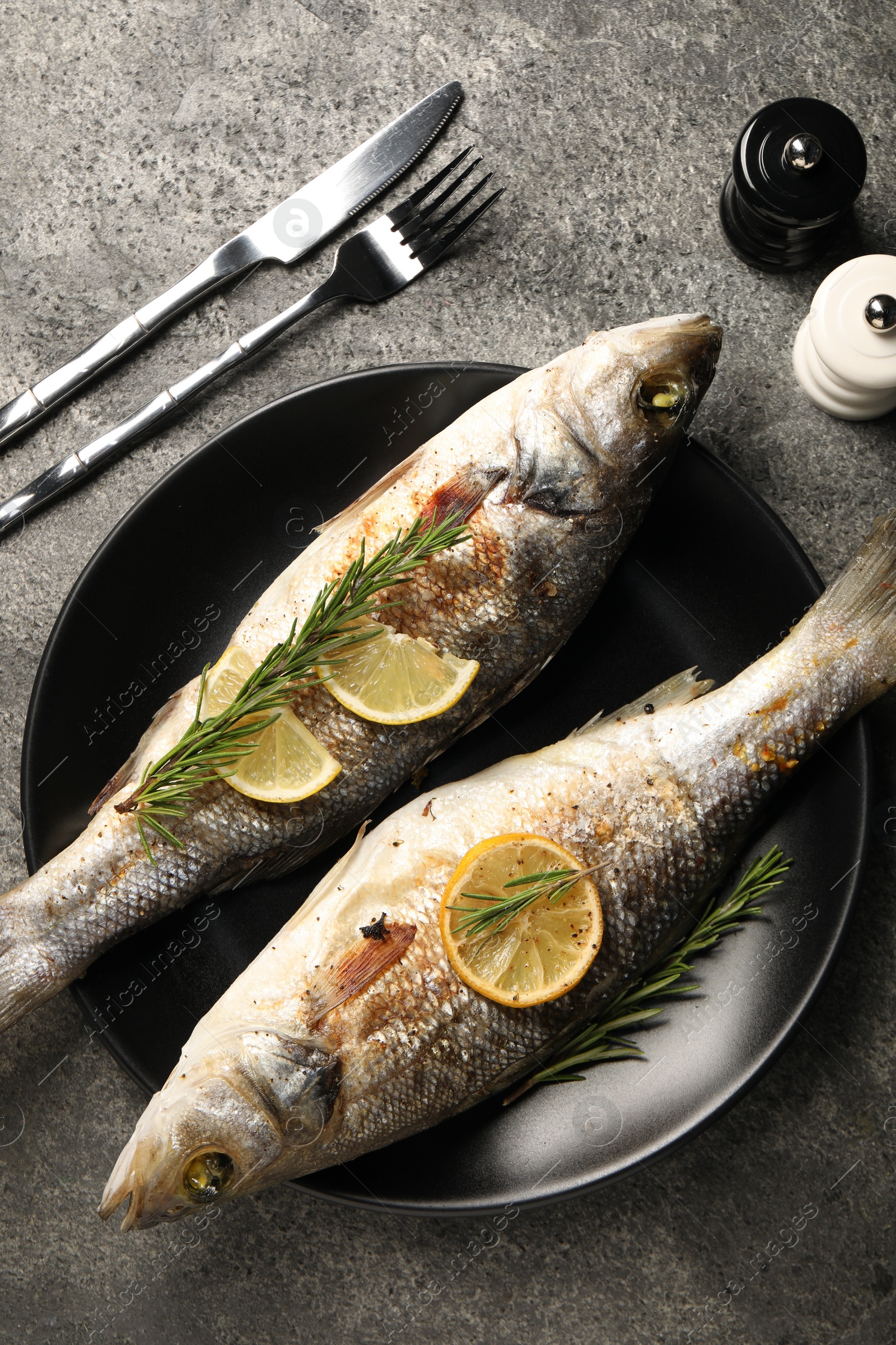 Photo of Delicious baked fish served on grey table, top view