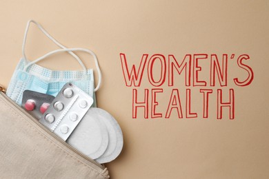 Photo of Bag with facial mask, pills and sanitary pads near words Women's Heath on beige background, top view