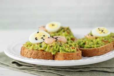 Slices of bread with tasty guacamole, eggs and shrimp on table, closeup