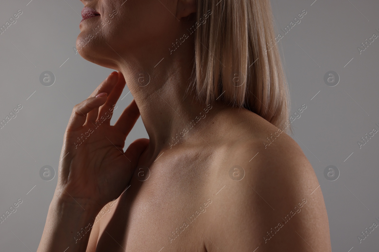 Photo of Woman touching her neck on grey background, closeup